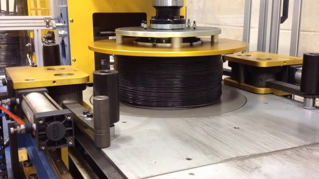 A machine for coiling and strapping steel wire automatically. A machine for coiling and strapping steel wire automatically.